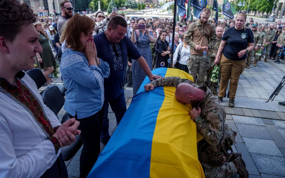 A Ukrainian serviceman cries over the coffin of Iryna Tsybukh