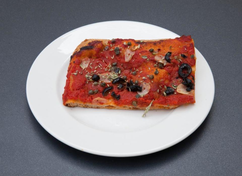 Pizza with tomato, olives, garlic, dried datterini, capers, oregano at Mike’s, Peckham, London.