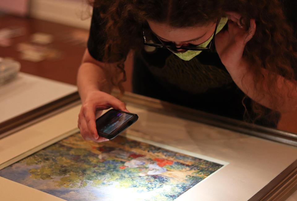 Kaitlyn Hof-Mahoney, Matheson History Museum curator of collections, examines "Three Women Washing" by Emmaline Buchholz at the museum on Wednesday. She was completing a report on its condition before the new exhibit is opened to the public.