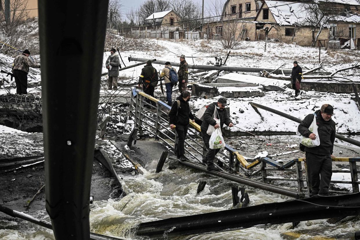 Civilians try to cross a river on a blown up bridge on Kyiv's northern front on March 1, 2022.