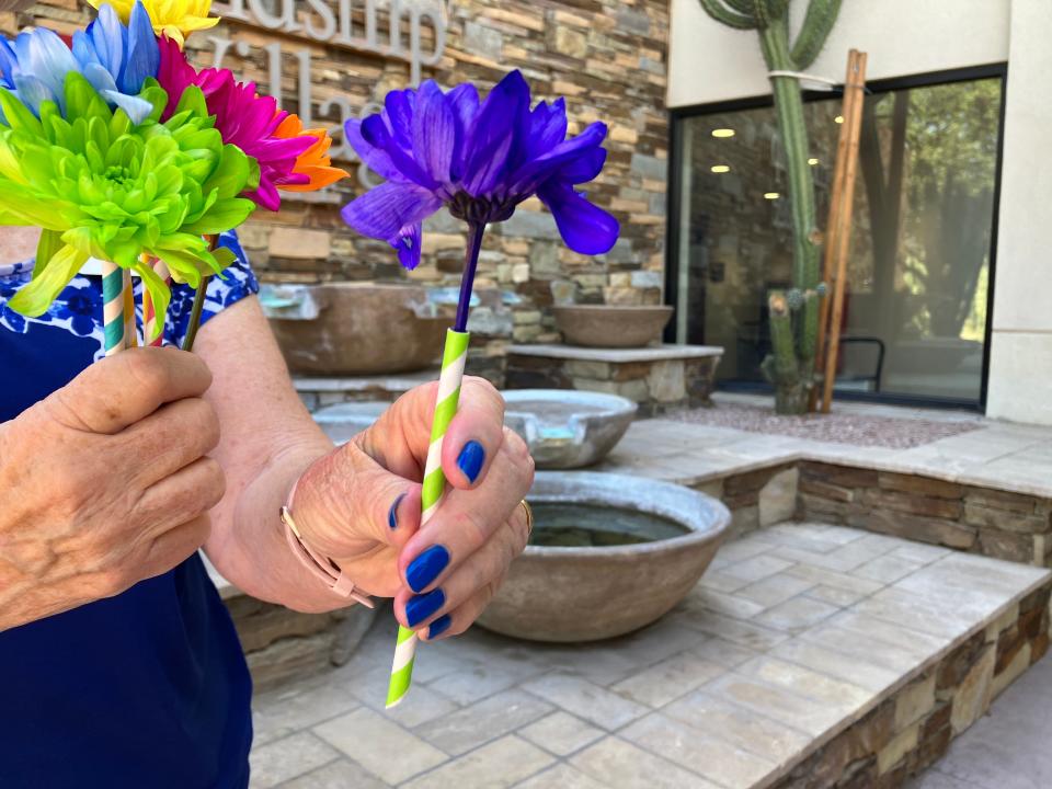 Retired clown Lida Mainieri offers a flower from a colorful bouquet.
