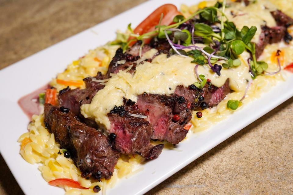 A peppercorn crusted New York strip steak, topped with white wine asiago sauce and served over red pepper orzo, is one of the dishes cooked up by the new chefs and owners of Che Bello restaurant in downtown Bloomington.