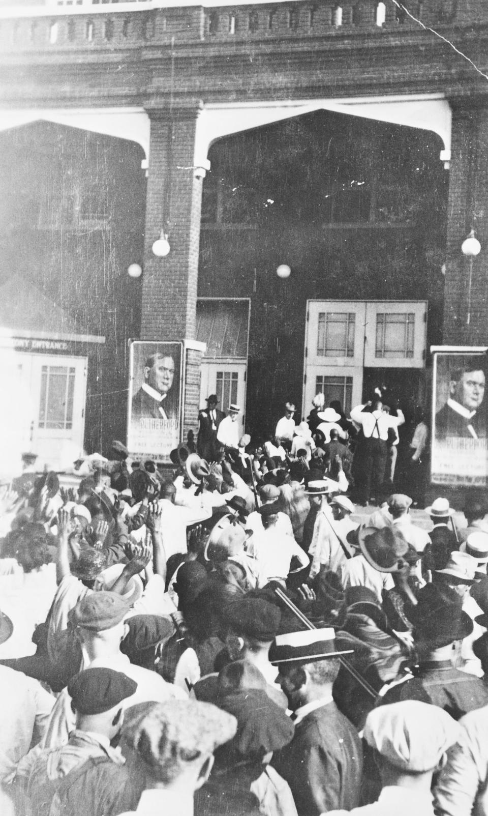 Black residents walk with arms raised, surrounded by armed white men during the Tulsa Race Massacre in 1921.