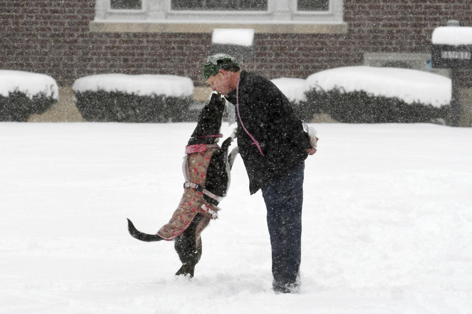 Chris Wheeler and his dog Milli share a treat as they play in the snow on the lawn in front of Adams Town Hall in Adams, Mass., on Sunday, Jan. 7, 2024. (Gillian Jones-Heck/The Berkshire Eagle via AP)