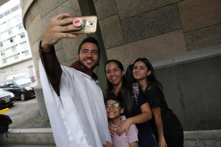 Venezuelan priest Luis Antonio Salazar uses a mobile phone to take a selfie with devotees after Sunday Mass at Chiquinquira church in Caracas