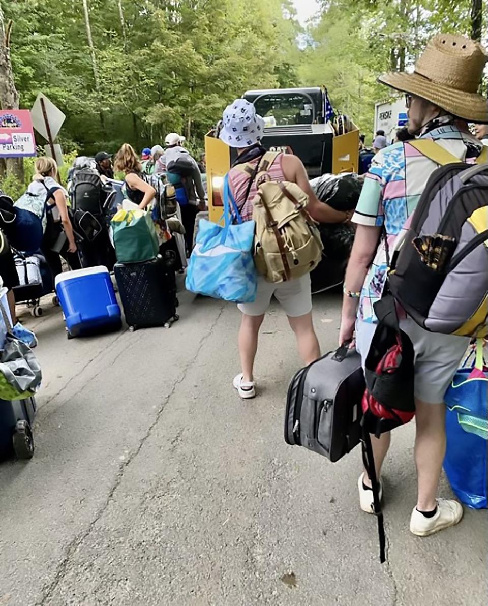 Festival-goers lug their camping supplies along the road to the camp grounds for Elements Music and Arts Festival near Lake Como in Wayne County in September. Attendees called out the festival for what they described as poor conditions, such as a lack of clean water, bathrooms, food and ADA-compliance.