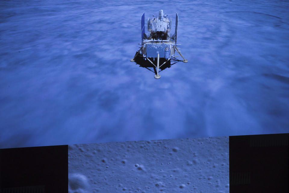 En esta imagen publicada por la agencia de noticias Xinhua, una pantalla muestra la nave espacial Ceng'e-5 tras alunizar y una foto de la superficie lunar, tomada por una nave de la sonda Chang'e 5 durante su alunizaje, en el Centro de Control Aeroespacial de Beijing (BACC) el martes 1 de diciembre de 2020. (Jin Liwang/Xinhua via AP)