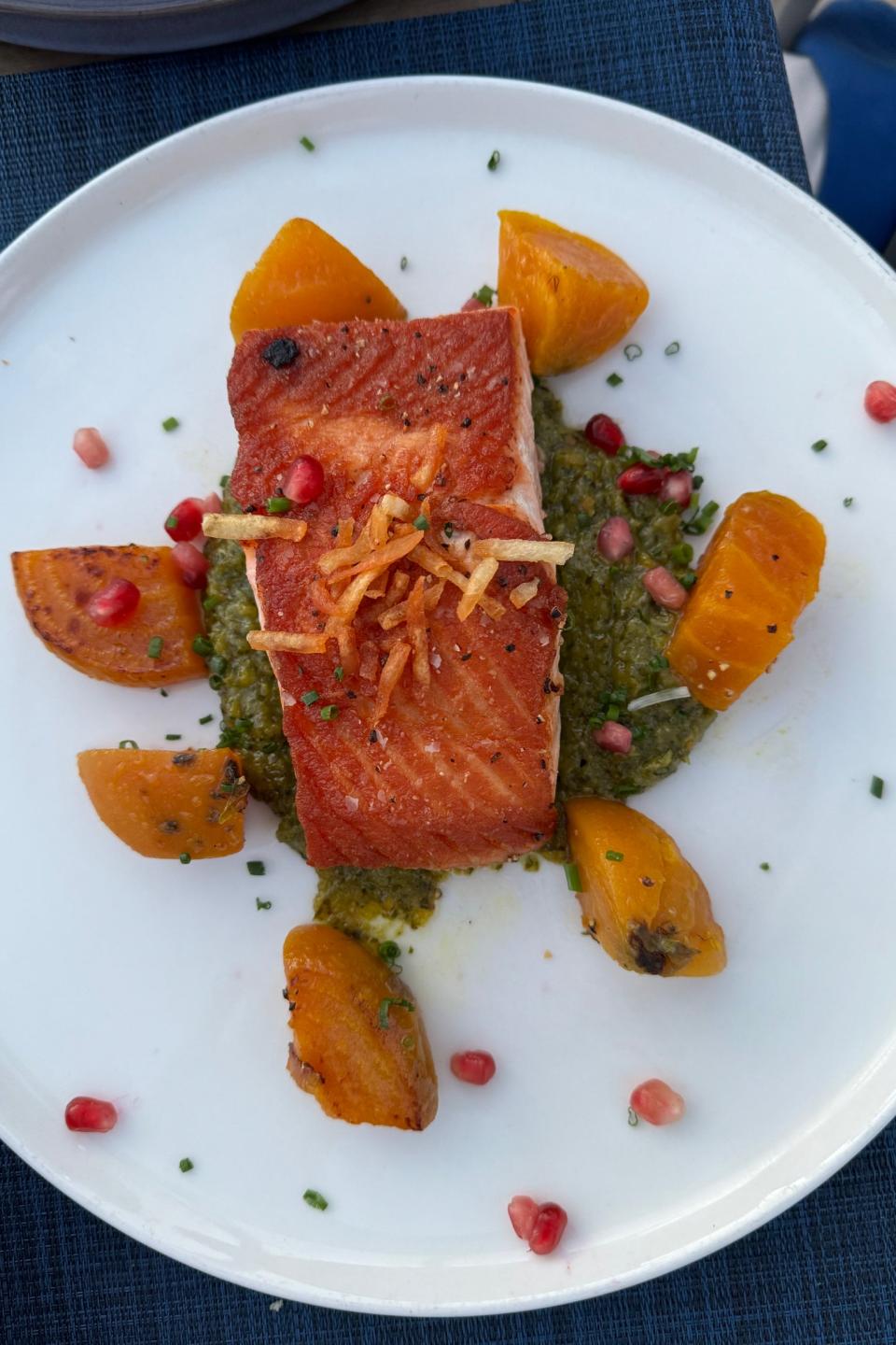 Grilled salmon with pesto and pomegranate on a plate, a gourmet meal presentation