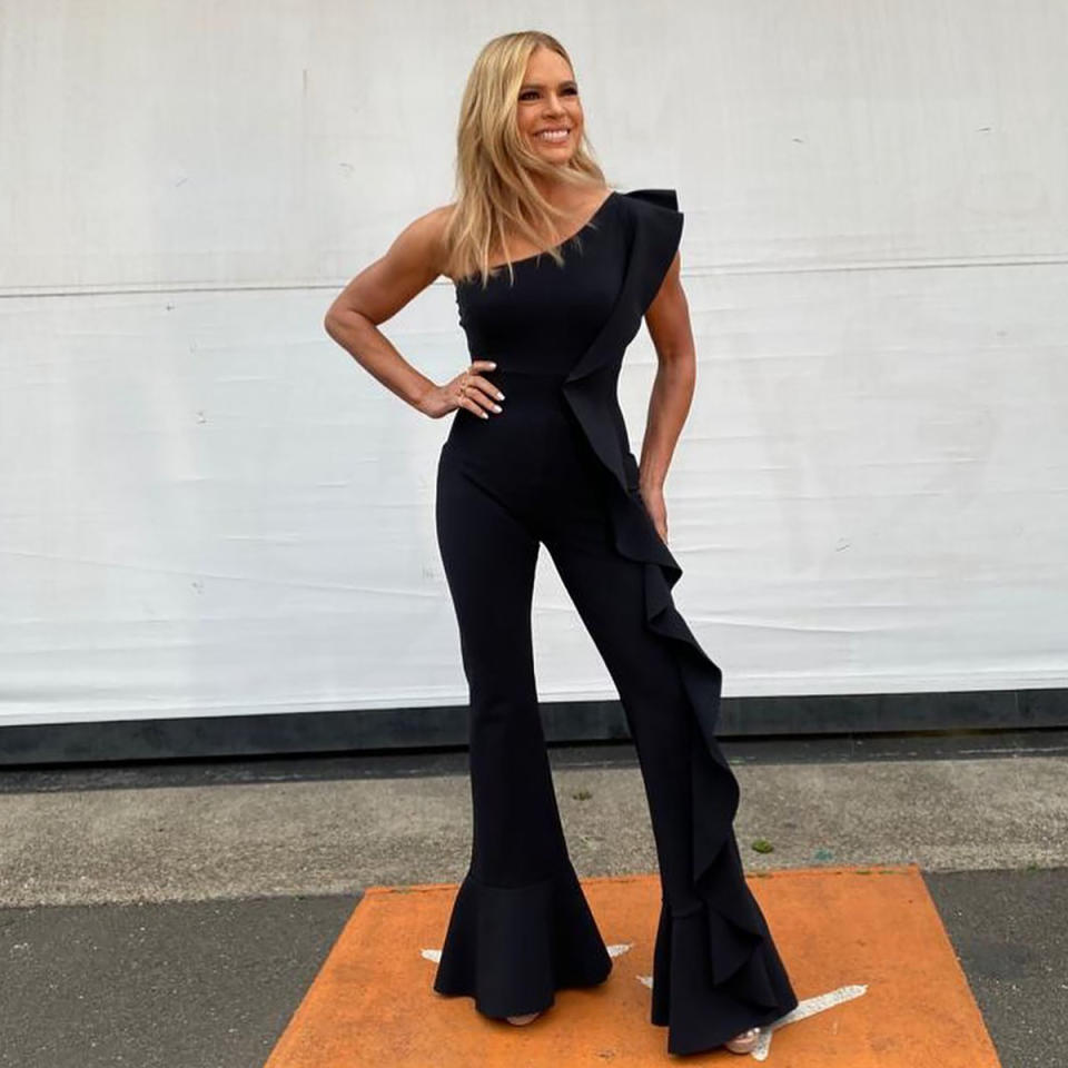 Sonia Kruger in a one shoulder black jumpsuit with a flared leg