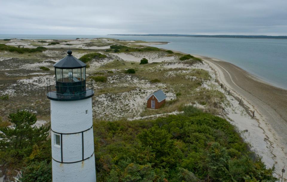 Sandy Neck Light in Barnstable can do little to brighten a gray Monday morning as the sand dunes looking west past the old slate roofed oil house are beginning to show their fall colors.