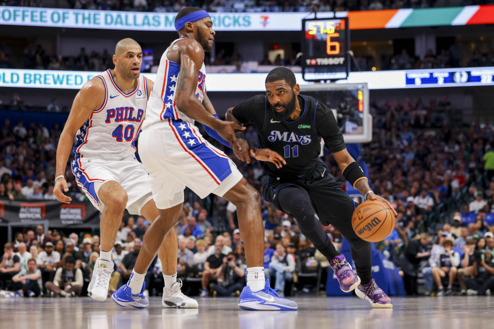 Dallas Mavericks guard Kyrie Irving (11) drives past Philadelphia 76ers forwards Paul Reed (44) and Nicolas Batum (40) during the first half of an NBA basketball game, Sunday, March 3, 2024, in Dallas. (AP Photo/Gareth Patterson)