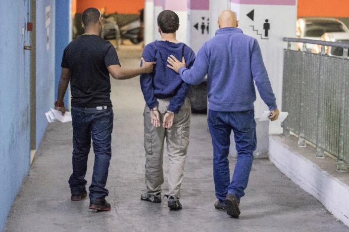 An Israeli-American teenager accused of making dozens of anti-Semitic bomb threats is escorted from an Israeli court in Rishon Lezion on March 23, 2017 (AFP Photo/JACK GUEZ)