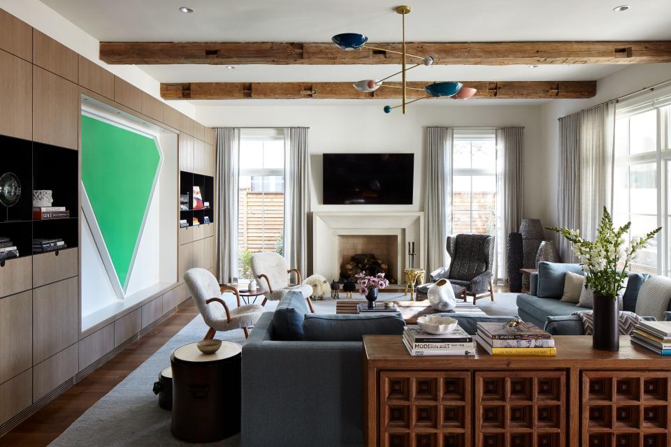 In the family room, in which cabinetry was custom designed to fit a triangular painting by Ellsworth Kelly titled Green Panel, a large square sectional from Dmitriy & Co. sits behind a 1960s Spanish console from Morentz. “It was a beautiful find,” says Liss. “It really works with the rustic beams and balances the modern nature of the millwork.”