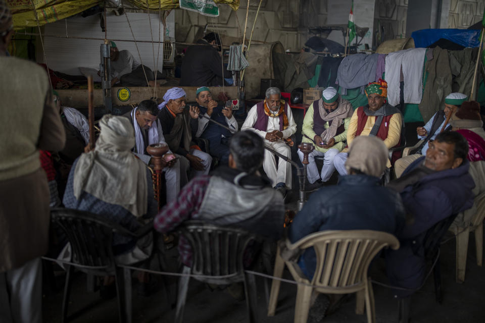 Farmers sit around a bonfire while blocking a major highway in a protest against new farm laws at the Delhi-Uttar Pradesh state border, India, Wednesday, Jan. 20, 2021. Farmers have been blockading highways connecting New Delhi to northern India for nearly seven weeks against new farm laws, obstructing transportation and dealing a blow to manufacturing and businesses in the north. Farmers fear the government will stop buying grain at minimum guaranteed prices and that corporations will then push prices down under the new laws. (AP Photo/Altaf Qadri)