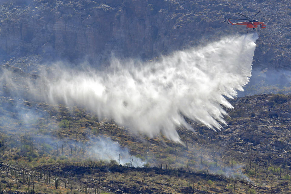 A Wildfire air attack crew battles the Bighorn Fire along the western side of the Santa Catalina Mountains, Friday, June 12, 2020, in Tucson, Arizona. Hundreds of homes on the outskirts of Tucson remain under an evacuation notice as firefighters work to keep the wildfire from moving downhill from canyons and ridges in the Coronado National Forest. (AP Photo/Matt York)