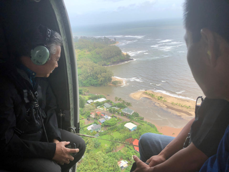 FILE - In this photo provided by the Office of the Governor, Hawaii, Hawaii Gov. David Ige, left, flies over the flood-damaged areas of the island of Kauai on April 16, 2018. Crisis response are two words that could sum up the Democrat's eight years leading Hawaii, which are due to wrap up when his successor Lt. Gov. Josh Green is inaugurated on Dec. 5, 2022. (Courtesy of Hawaii Governor's Office via AP, File)