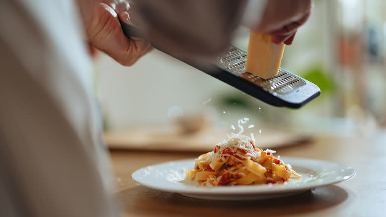 Grating cheese onto pasta