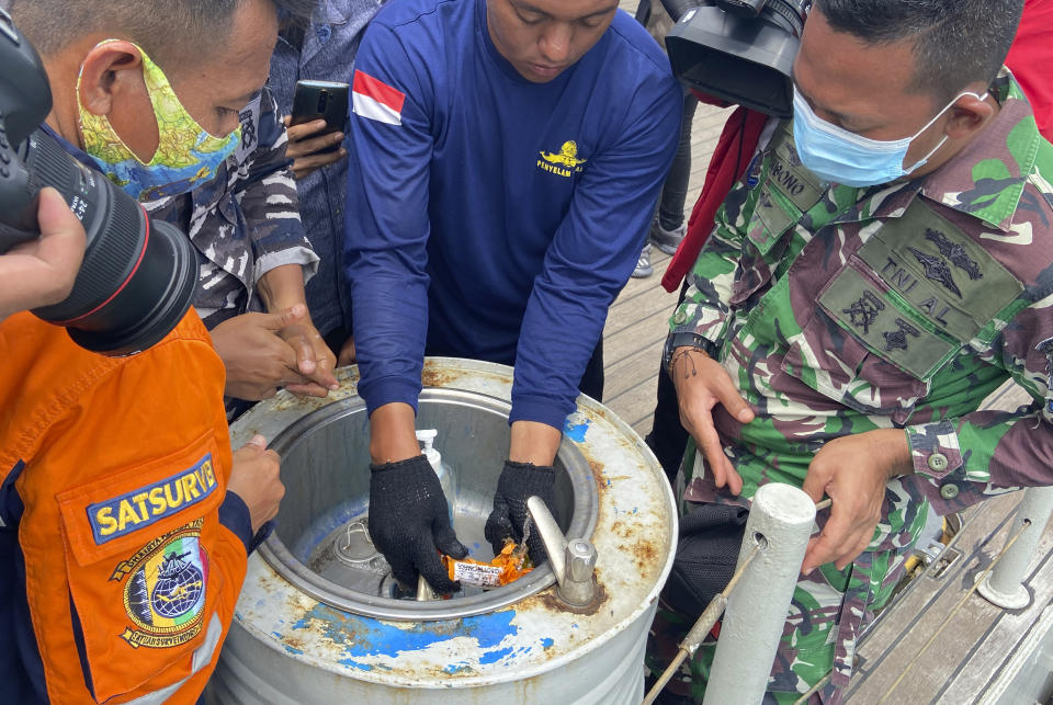 Indonesian navy personnel inspect a part the flight data recorder of Sriwijaya Air flight SJ-182 retrieved from the Java Sea where the passenger jet crashed in waters off the Tanjung Priok Port, Tuesday, Jan. 12, 2021. Indonesian navy divers searching the ocean floor on Tuesday recovered the flight data recorder from a Sriwijaya Air jet that crashed into the Java Sea with 62 people on board, Saturday, Jan. 9, 2021. (AP Photo/Fadlan Syam)