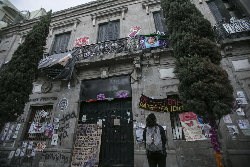 A woman looks at the Mexico’s Human Rights Commission (CNDH) headquarters which has been occupied for almost three months by women’s rights activists who have converted it into a refuge for victims of gender violence in Mexico City, Tuesday, Nov. 17, 2020. Feminist activists are occupying the building to demand justice for the victims of sexual abuse, femicide, and other gender violence, and are hosting some women and their children after the government either failed to solve or investigate sexual attacks on their guest’s daughters. (AP Photo/Ginnette Riquelme)