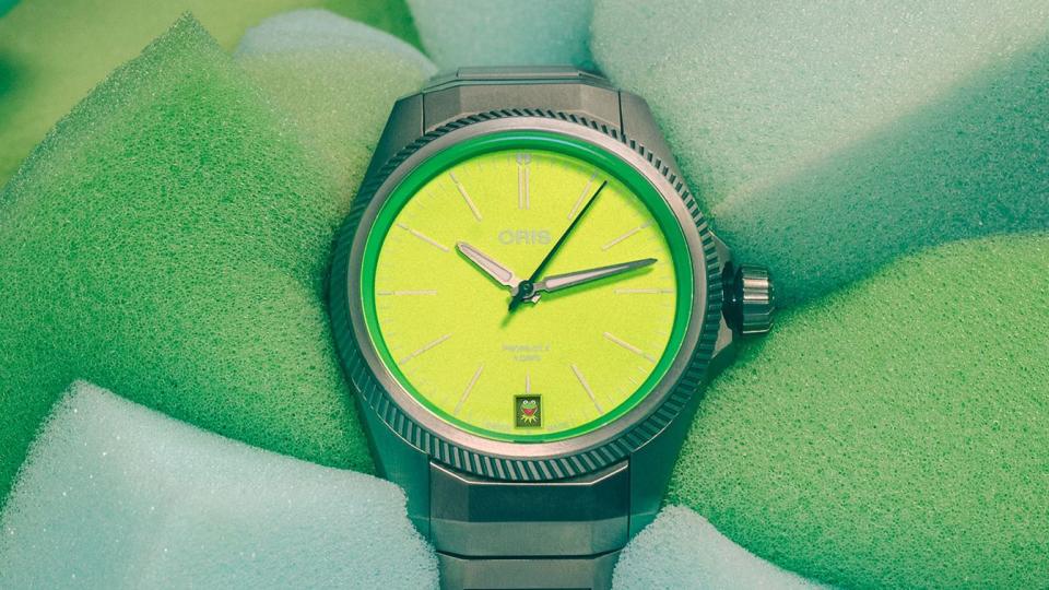 yellow and green watch with kermit in day slot wrapped around a piece of light green foam