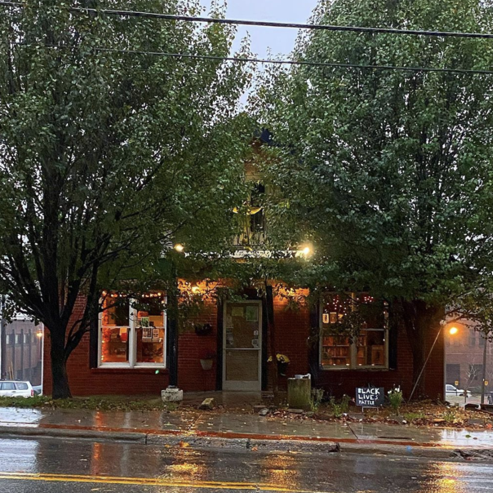 A small bookstore glows warmly as rain falls outside (@foggypinebooks / Instagram)