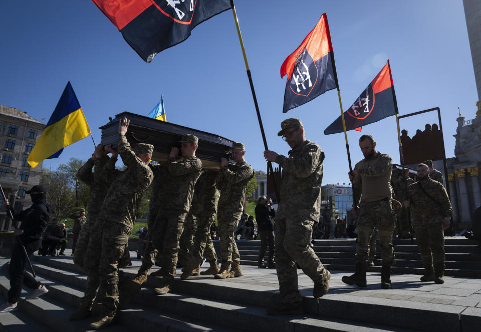 People kneel as soldiers carry the coffins of Ukrainian servicemen Serhiy Konoval and Taras Petrushun, who were killed in a battle with the Russian troops, during the funeral ceremony in Independence square in Kyiv, Ukraine, Tuesday, Apr. 9, 2024. (AP Photo/Efrem Lukatsky)