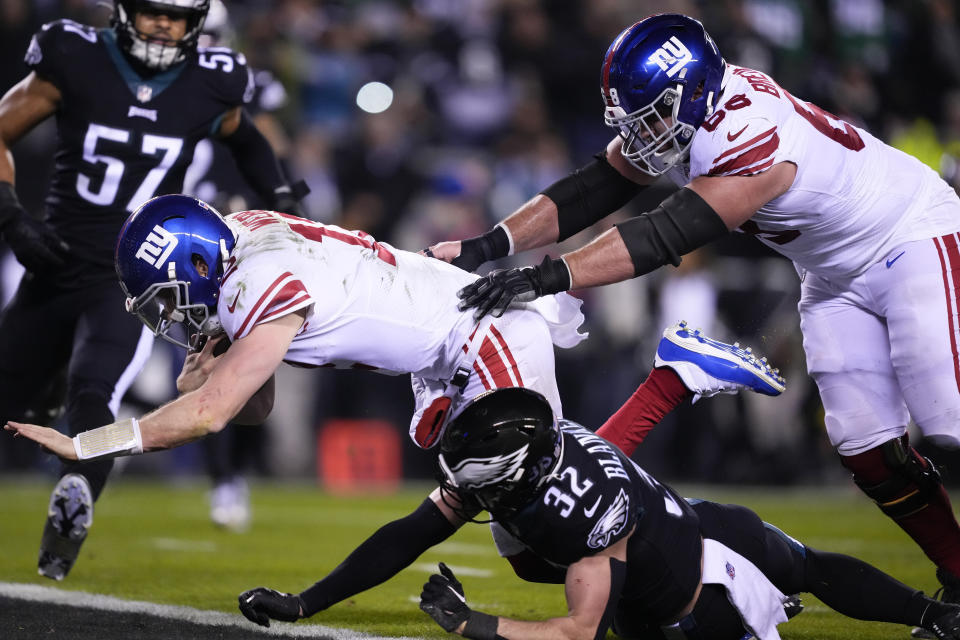 New York Giants quarterback Davis Webb (12) plows over Philadelphia Eagles safety Reed Blankenship (32) while scoring on a touchdown run during the second half of an NFL football game, Sunday, Jan. 8, 2023, in Philadelphia. Giants guard Ben Bredeson (68) helps on the play. (AP Photo/Matt Rourke)