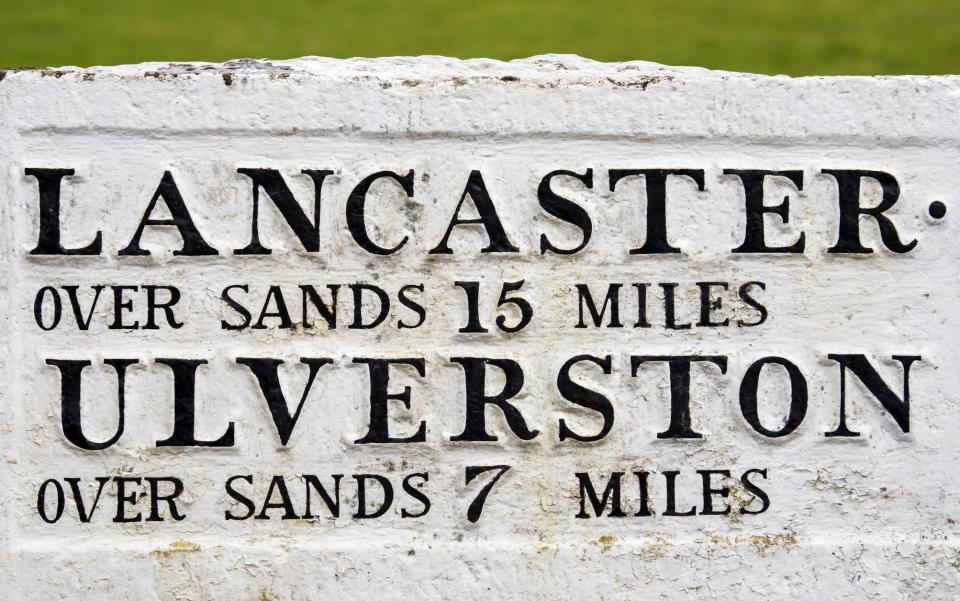 An old road sign giving distances to towns across the sands of Morecambe Bay in Cartmel, Cumbria, UK - Getty/Corbis