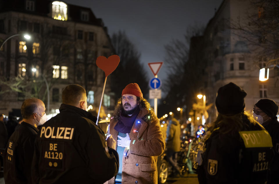 Police officers stop an anti-vaccination activist, who refuses to wear a face mask, trying to disturb a counter demonstration in Berlin, Germany, Monday, Jan. 24, 2022. A growing number of Germans have recently joined grassroots initiatives, local groups and spontaneous demonstrations to speak out against vaccination opponents, conspiracy theorists and far-right extremists who have led protests against COVID-19 measures in Germany. (AP Photo/Markus Schreiber)