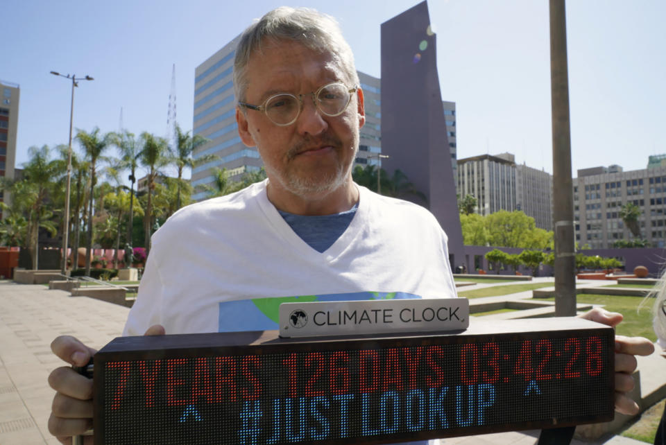 FILE - Adam McKay, director of the film "Don't Look Up," holds a Climate Clock as he joins members of the Youth Climate Los Angeles coalition and others protesting climate change at Pershing Square in Los Angeles, Friday, March 18, 2022. On Tuesday Sept. 20, 2022, McKay announced a $4 million donation to the Climate Emergency Fund, an organization dedicated to getting money into the hands of activists engaged in disruptive, nonviolent demonstrations urging swifter action on climate change. (AP Photo/Damian Dovarganes, File)