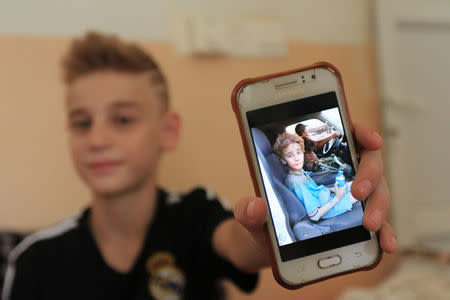 A Yazidi boy, twelve year-old Imad Tammo rescued from Islamic State militants by the Iraqi army, holds up a phone showing a picture of himself when he was rescued in Sina neighbourhood outside of Duhok, Iraq July 25, 2017. REUTERS/Ari Jalal