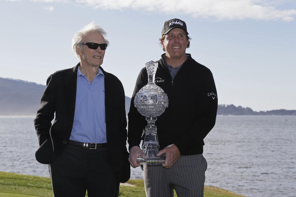 Phil Mickelson poses with his trophy and Clint Eastwood on the 18th green of the Pebble Beach Golf Links after winning the AT&T Pebble Beach Pro-Am golf tournament Monday, Feb. 11, 2019, in Pebble Beach, Calif. (AP Photo/Eric Risberg)