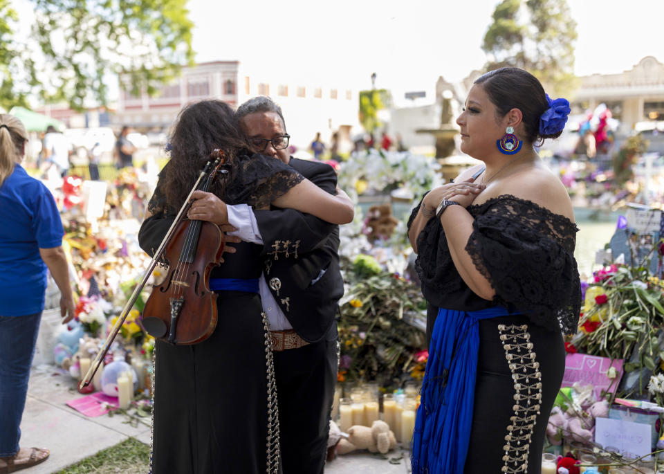 Anthony Medrano, al centro, abraza a un colega músico en un monumento conmemorativo improvisado y en crecimiento para los estudiantes y maestras asesinados en la primaria Robb que surgió en la plaza pública de Uvalde, Texas, el 1 de junio de 2022. (Ivan Pierre Aguirre/The New York Times).
