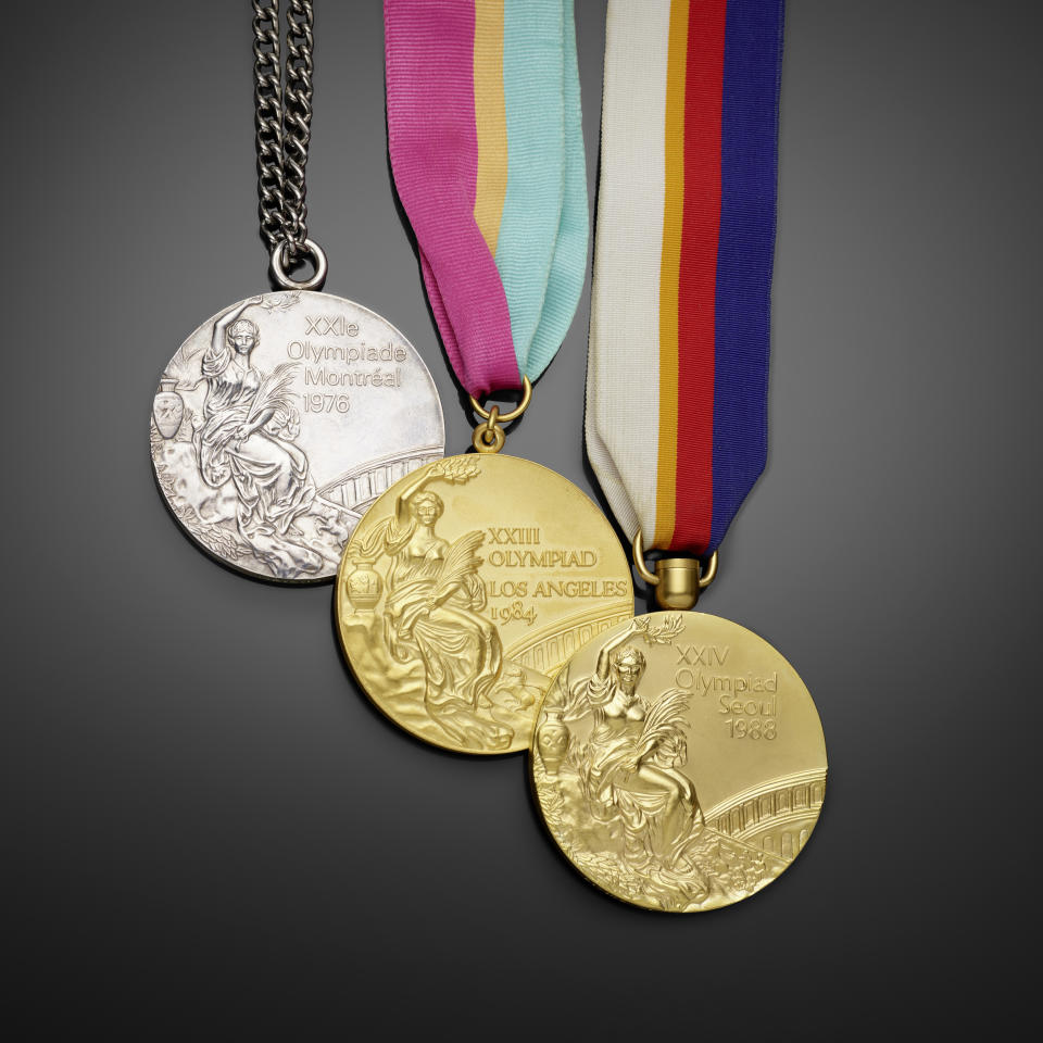 The silver medal is on a metal chain, and the golds have multicolored silk ribbons, one striped in pink, orange and aqua, and won in white, orange, red and navy blue.