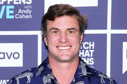 Shep Rose smiling in a navu, zebra patterned, shirt in front of the WWHL step and repeat in New York City.