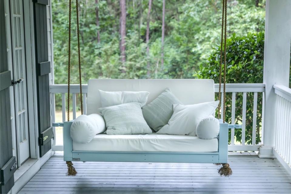 Modern porch swing on porch with lots of comfortable pillows