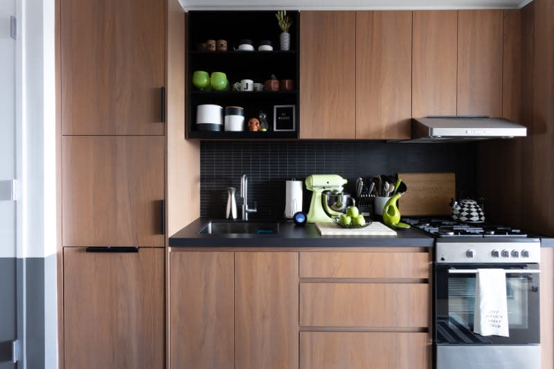 Kitchen with wood cabinets, black tile and countertops, green accents