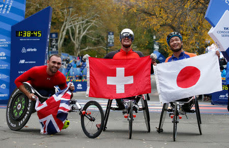 The winners of the wheelchair race, 2nd place winner John Charles Smith of Uinted Kingdom (L), winner Marcel Hug of Switzerland (C) and 3rd place winner Sho Watanabe of Japan (R) celebrate at the finish line of the New York City Marathon after winning the wheelchair race in Central Park in New York, U.S., November 5, 2017. REUTERS/Brendan McDermid