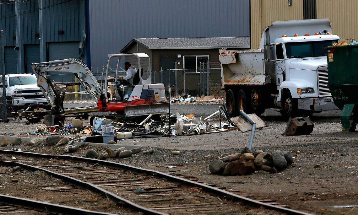 An excavator prepares to haul away pieces of abandoned recreational vehicles and trailers on Railroad Avenue in downtown Kennewick.