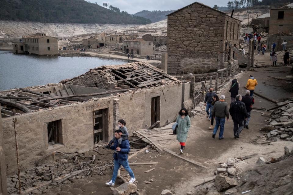 People walk among damaged buildings in the abandoned village of Aceredo, which was was flooded in 1992 as part of a hydro-electric power project but has emerged as a consequence of the ongoing drought (EPA)