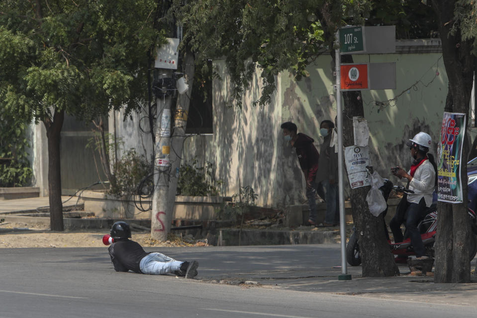 Anti-coup protesters take cover as a convoy of soldiers and policemen arrive in Mandalay, Myanmar, Wednesday, March 10, 2021. (AP Photo)