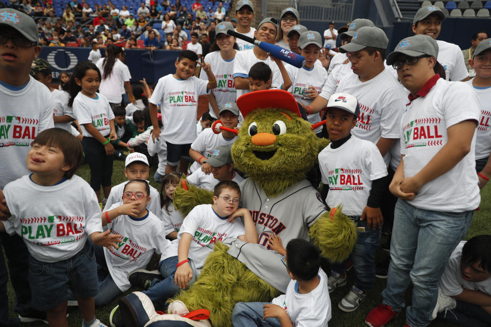 Orbit, la mascota de los Astros de Houston, posa con los participantes de evento Play Ball de las Grandes Ligas para niños de 5 a 13 años en Monterrey, México, el sábado 4 de mayo de 2019. (AP Foto/Rebecca Blackwell)