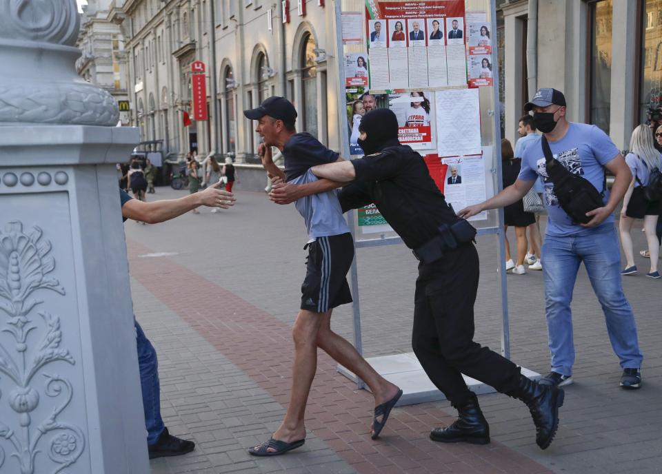 Belarusian police officers detain a man in Minsk, Belarus, Saturday, Aug. 8, 2020. On Saturday evening, police arrested at least 10 people as hundreds of opposition supporters drove through the center of the capital waving flags and brandishing clenched-fist victory signs from the vehicles' windows. The presidential election in Belarus is scheduled for August 9, 2020. (AP Photo/Sergei Grits)