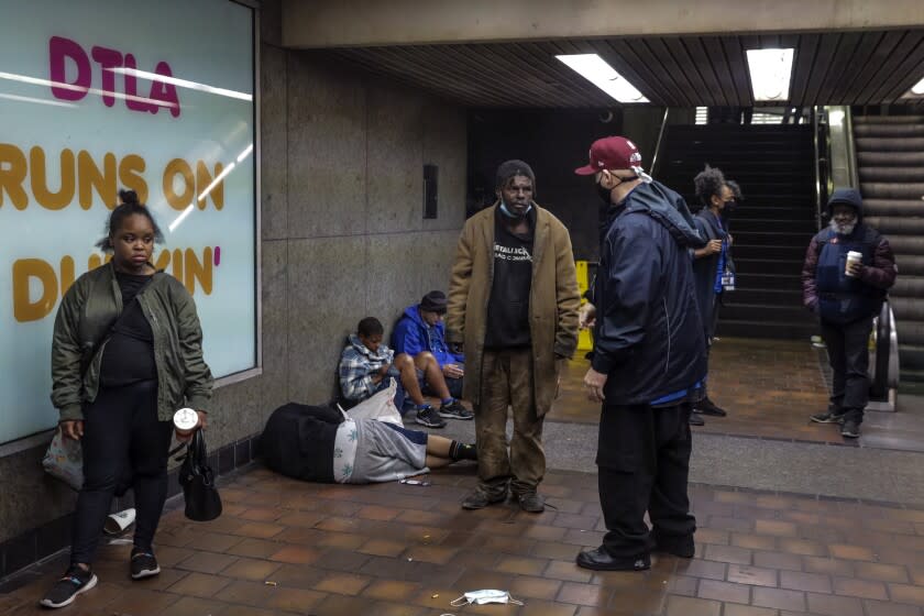 Los Angeles, CA - March 15: Marc Deall, in baseball cap center, and other members of People Assisting The Homeless (PATH) check on welfare of homeless folks sleeping in front of the closed entrance of 7th. Street Metro station on Tuesday, March 15, 2022 in Los Angeles, CA. (Irfan Khan / Los Angeles Times)