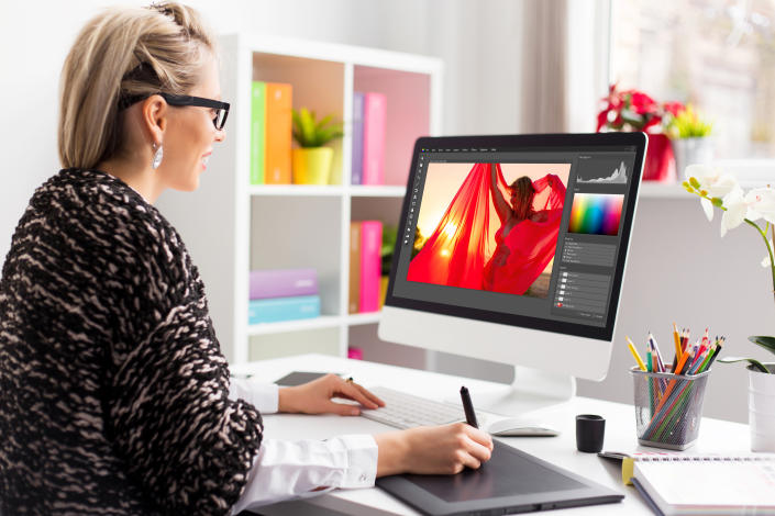 Woman retouching photo on computer.  The software interface is fully constituted.