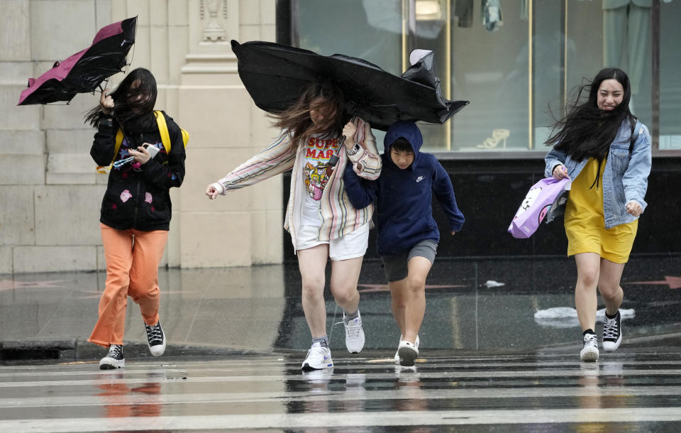 Pedestrians fight wind and rain as they cross Hollywood Boulevard during Tropical Storm Hilary, Sunday, Aug. 20, 2023, in Los Angeles. (AP Photo/Chris Pizzello)