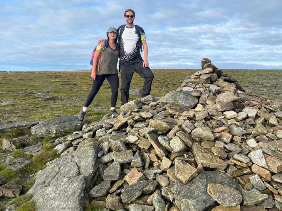 Anabel and her partner Chris at the peak. There is a large formation of rocks next to them.