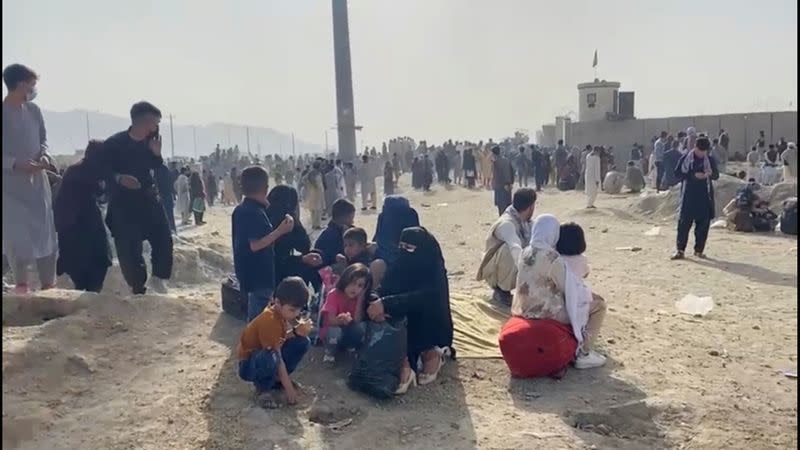 FILE PHOTO: People gathered outside the airport react to gunfire, in Kabul