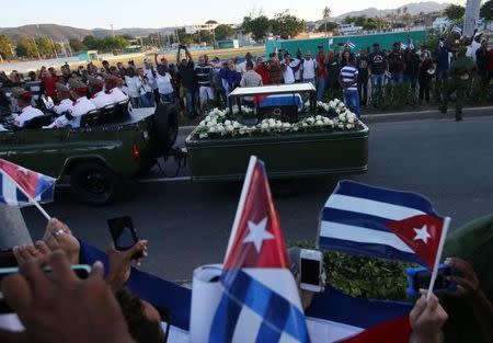 People watch the cortege carrying the ashes of Cuba's former President Fidel Castro drive toward Santa Ifigenia cemetery in Santiago de Cuba, Cuba, December 4, 2016. REUTERS/Carlos Barria