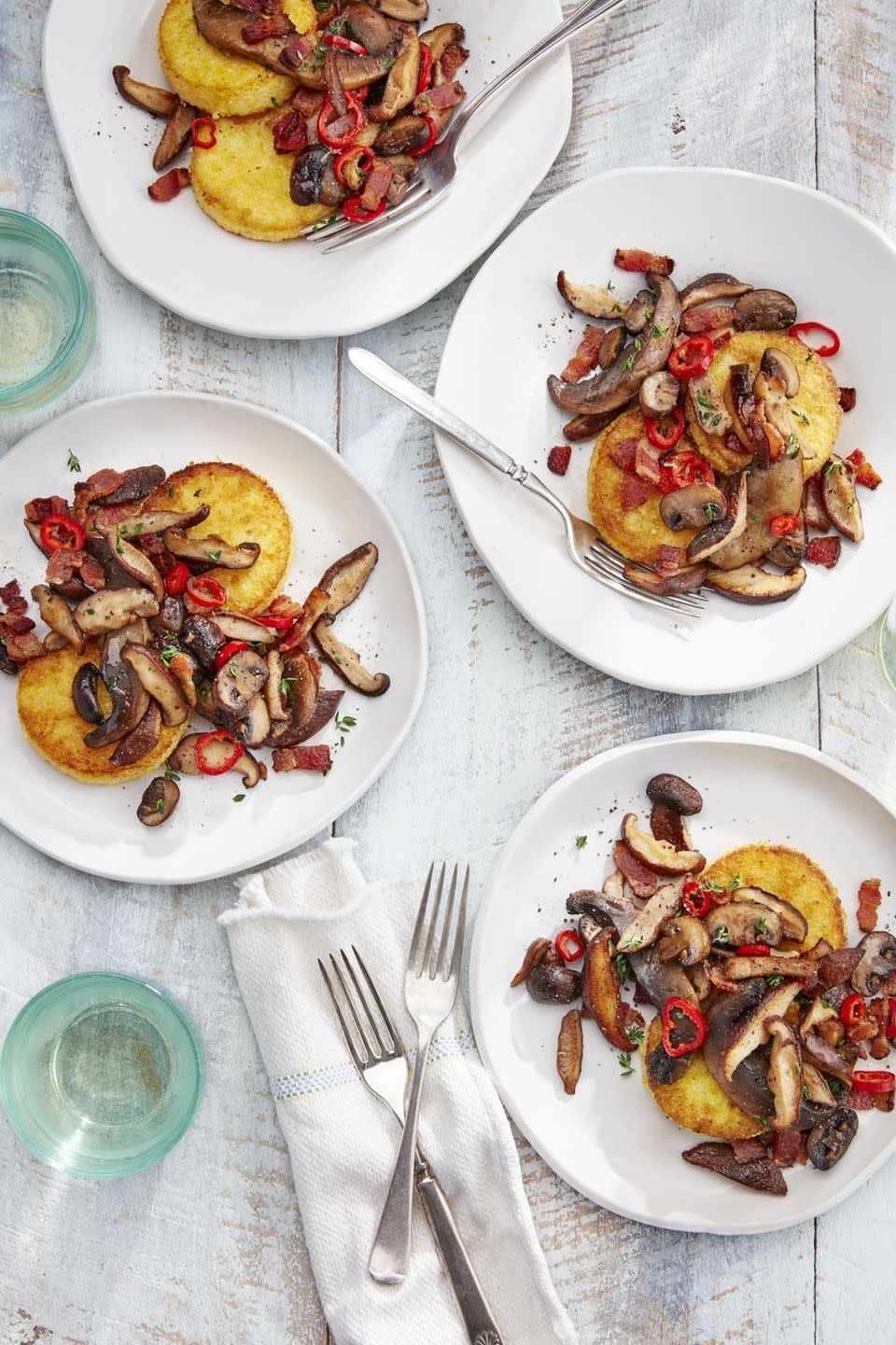 polenta cakes with sauteed mushrooms on white plates with silverware